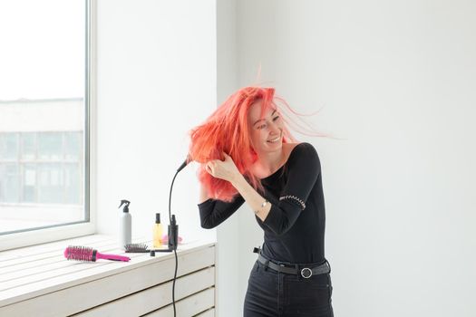 Hairdresser, beauty salon and people concept - young woman hair stylist with hair dryer on white background.