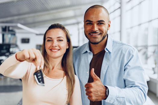 Happy excited couple or family buying a new car and showing keys