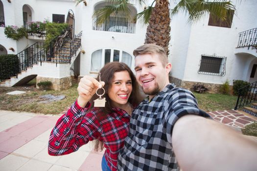 New Home, real estate and moving concept - Funny young couple showings keys from new house