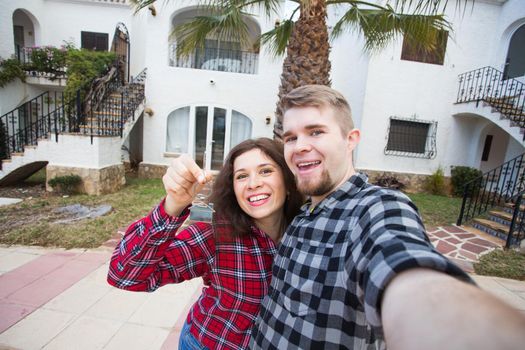 Property, real estate and rent concept - Happy smiling young couple showing a keys of their new house.