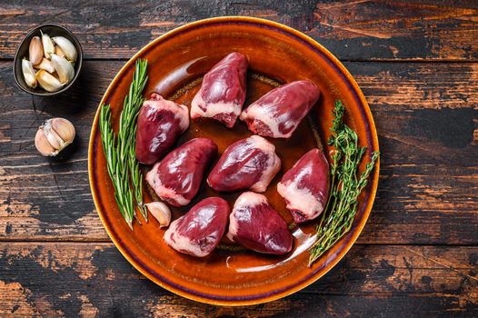 Fresh Raw turkey hearts offal giblets with thyme and rosemary. Dark wooden background. Top view.