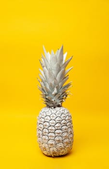 White whole fresh pineapple placed on table in modern studio on yellow background