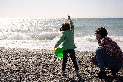 Mother and little daughter having fun on the beach in winter