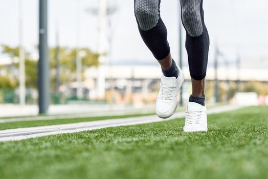Feet of black man starting running in urban background. Male doing workout outdoors.