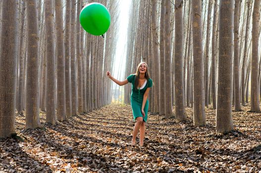 Beautiful blonde girl, dressed in green, laughing in the forest