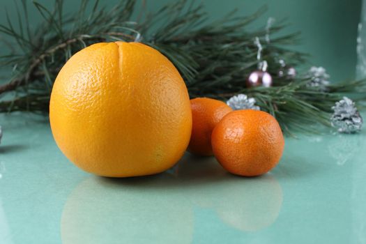 tangerines and orange lie near the Spruce tree on a green background. New Year's Christmas atmosphere holiday.