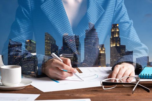 Corporate consultant analyze financial diagram. Real estate investment company double exposure concept with skyscrapers. Analyst working at workplace in office. Business accounting and management.