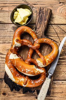 Baked pretzels with sea salt on a rustic wooden cutting board. Wooden background. Top view.