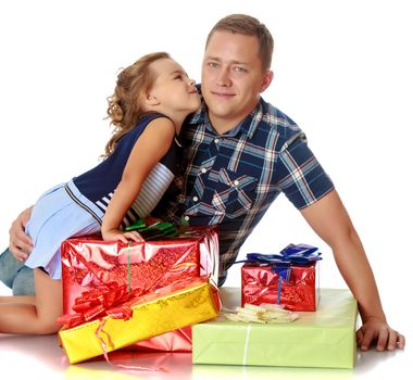 Gentle little girl kissing her beloved father, who is sitting on the floor surrounded by a variety of beautifully packaged boxes with gifts.Isolated on white background.