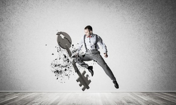 Determined businessman jumping and breaking with kick stone key figure