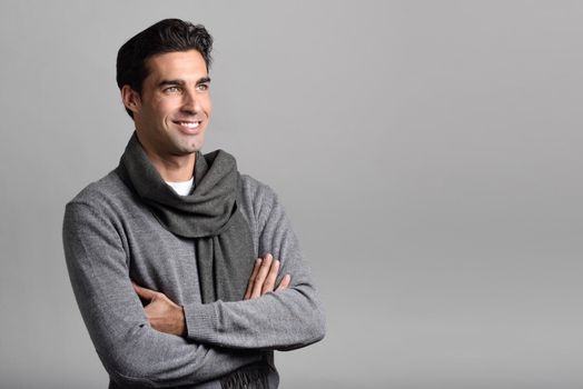 Handsome man wearing winter clothes smiling on white background. Young male with swater and scarf. Studio shot