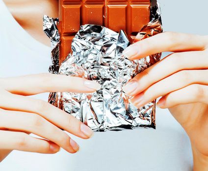 woman eating chocolate, close up hands with manicure french nails holding candy, beautiful fingers, lifestyle people concept