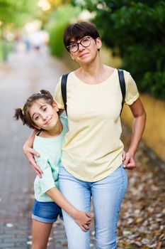 Middle-aged mother and daughter standing toghether on the street