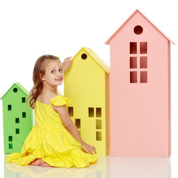 A cute little girl is playing with wooden houses. The concept of family happiness, play, creative development of the child.