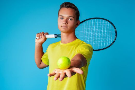 Young man tennis player in sportswear posing against blue background close up