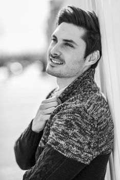 Portrait of a young handsome man, model of fashion, with modern hairstyle in urban background, wearing casual clothes.