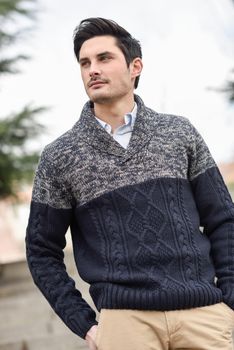 Portrait of a young handsome man, model of fashion, with modern hairstyle in urban background, wearing casual clothes.