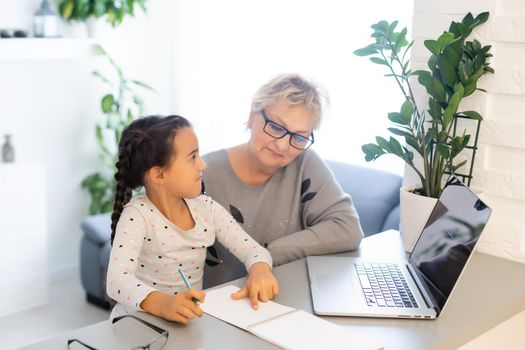 Helpful granny. Helpful loving granny assisting her cute granddaughter making homework