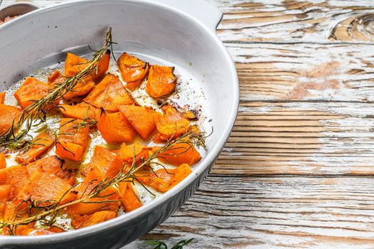 Oven baked pumpkin slices with rosemary, healthy vegetarian food. Wooden background. Top view. Copy space.
