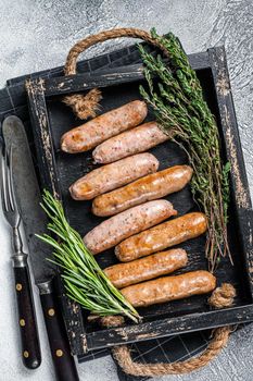 Roasted Bratwurst Hot Dog sausages in a wooden tray with herbs. White background. Top View.