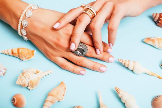 beautiful woman hands with pink manicure holding plate with pearls and sea shells, luxury jewelry concept close up