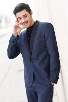 Portrait of an attractive young businessman outdoors, wearing modern suit.