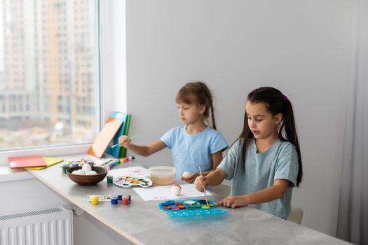 two little girls at the table with paints for drawing