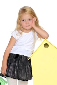 A cute little girl is playing with wooden houses. The concept of family happiness, play, creative development of the child.