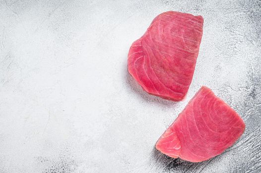 Two raw tuna steaks on rustic table. White background. Top view. Copy space.