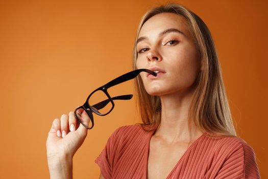 Portrait of a pensive thoughtful young woman.against orange background