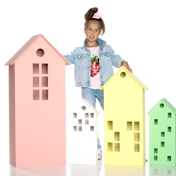 A cute little girl is playing with wooden houses. The concept of family happiness, play, creative development of the child.