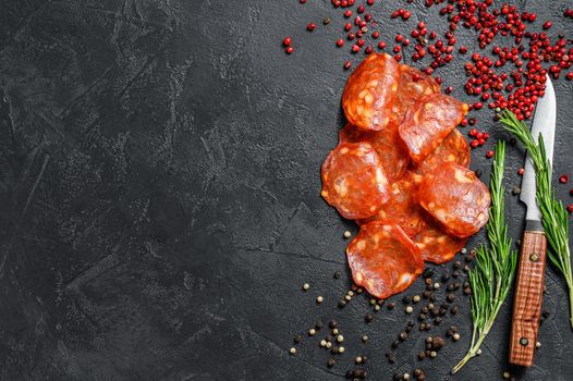 Chorizo sausage thin cut. Spanish salami with spices, paprika, pepper. Spicy food. Black background. Top view. Copy space.