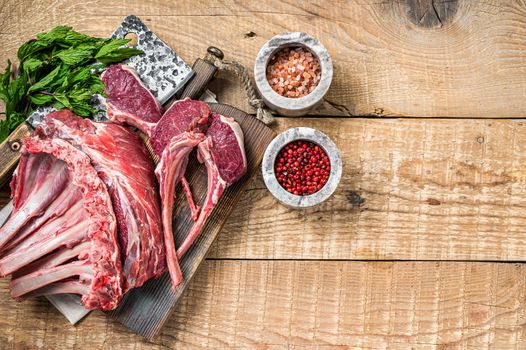 Raw Rack and rib chops of lamb, mutton on a butcher cutting board. Wooden background. Top view. Copy space.