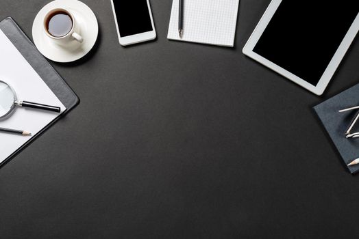 Top view of modern workplace with tablet computer. Flat lay black surface with smartphone and notebook with pen. Top view coworking workspace and freelance. Digital technology and mobile lifestyle.