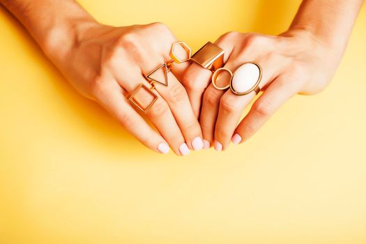 woman hands with manicure and jewelry ring on yellow background, beauty style concept close up