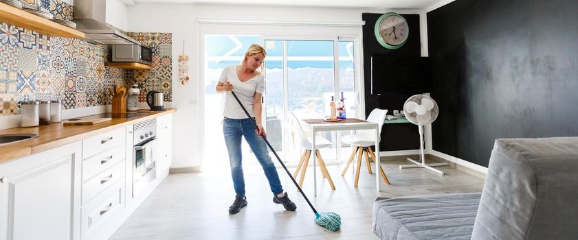 Cleaning concept. Young woman washing floor on the kitchen