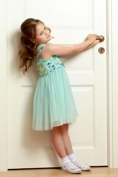 A nice little girl is standing by the door. The concept of family happiness and a home.