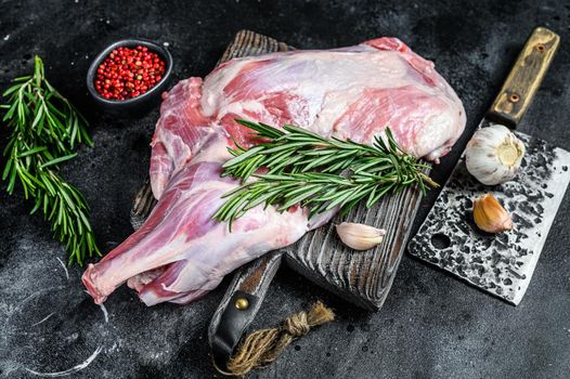 Raw lamb shoulder meat ready for baking with garlic, rosemary. Black background. Top view.