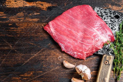 Raw flank beef marbled meat steak on a cleaver. Dark Wooden background. Top view. Copy space.