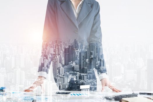 Businesswoman in suit standing near office desk with financial charts. Meeting in conference room. Business idea presentation, analyze and strategy planning. Entrepreneurship double exposure concept