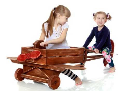 Two girls sister play with a wooden plane. The concept of a happy childhood, playing in the family. Isolated on white background.