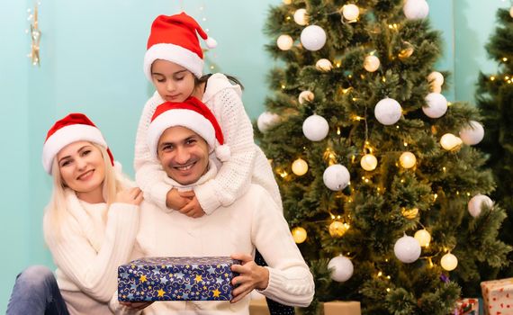 happy young family with one child holding christmas gift and smiling at camera