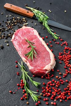 Raw striploin steak or strip New York with herbs. Black background. Top view.