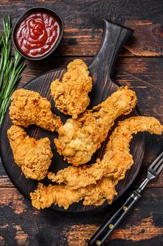 Breaded chicken drumstick, leg, wing and breast tenders strips. Dark Wooden background. Top view.