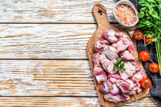 Raw uncooked chicken gizzards, stomach on a cutting board. wooden background. Top view. Copy space.