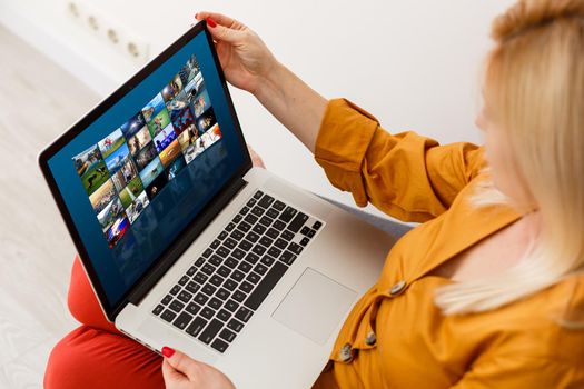 Young Woman Sitting Near The Sofa Watching Video On Laptop
