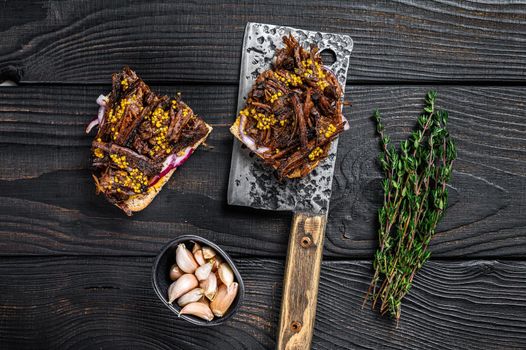 Brisket Sandwich with smoked beef meat on a meat cleaver. Black wooden background. Top view.