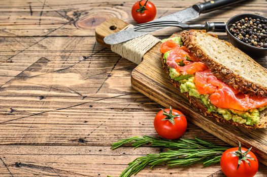 Sandwich with smoked salmon, avocado and egg. Wooden background. Top view. Copy space.