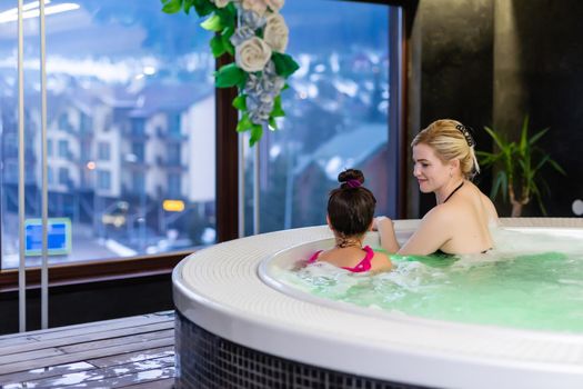 Mother and daughter relaxing in private jacuzzi. People smiling. Travel, summer and family concept.
