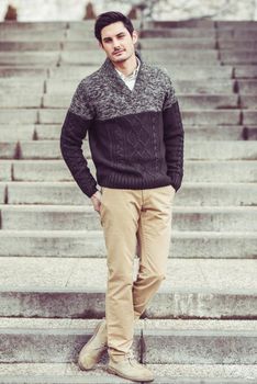 Portrait of a young handsome man, model of fashion, with modern hairstyle in urban background, wearing casual clothes.